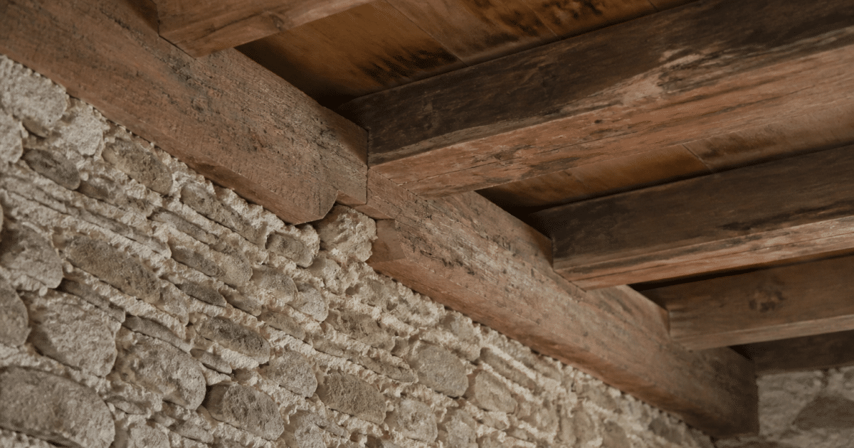 Mur vertical en pierre supportant poutres bois maison ancienne