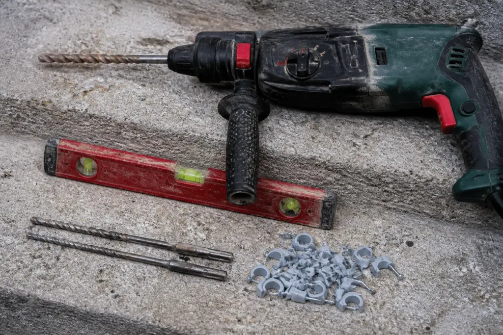 Perceuse, mèches béton, niveau et colliers de fixation réunis