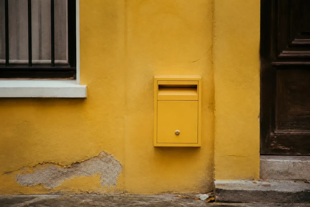 Facade jaune d'un immeuble avec boite aux lettres