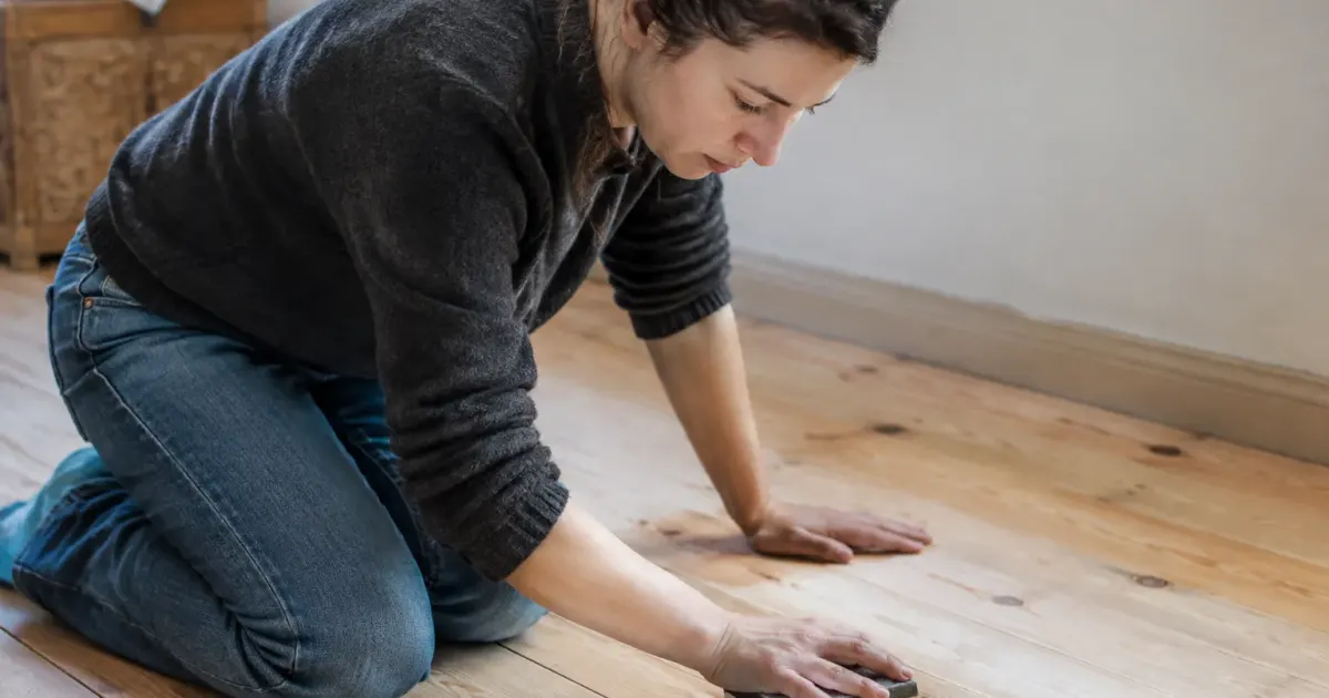 Femme agenouillee frottant des lames de bois clair