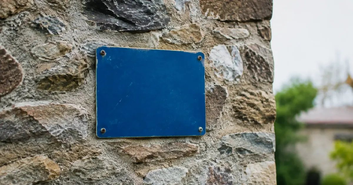 Panneau bleu accroche sur un mur de pierre