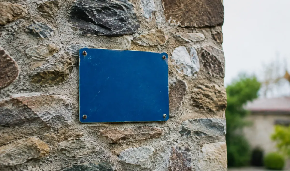 Panneau bleu accroche sur un mur de pierre
