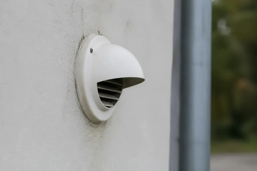 Petit extracteur blanc fixe sur un mur exterieur